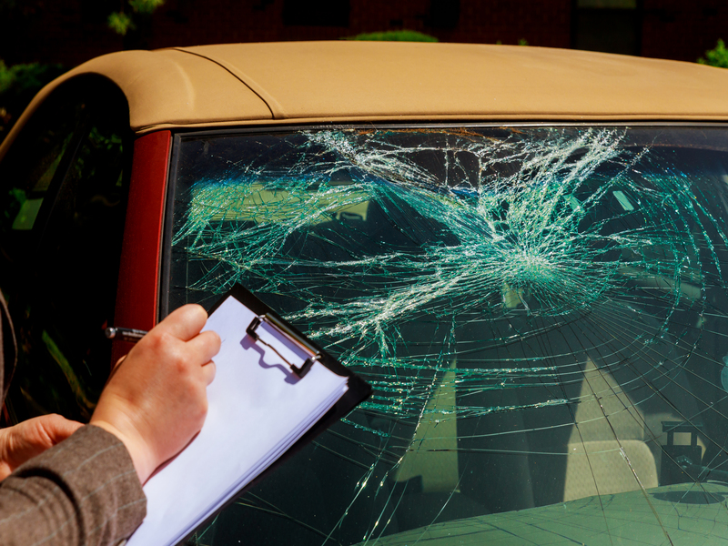 Insurance agent estimating the cost of damaged windshield after a car accident with an animal on the road